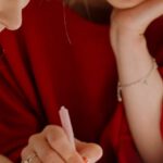 Peer Tutoring - Woman in Red Shirt Holding Pen Writing on White Paper