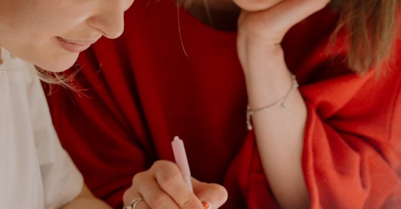 Peer Tutoring - Woman in Red Shirt Holding Pen Writing on White Paper
