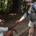 Fitness Journey - Hiker holding hand of black friend on road