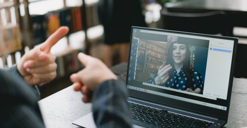 Language Barriers - Young lady learning sign language during online lesson with female tutor