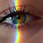 Mind Mapping - Closeup of crop anonymous sad female with green eyes and rainbow light on face looking at camera