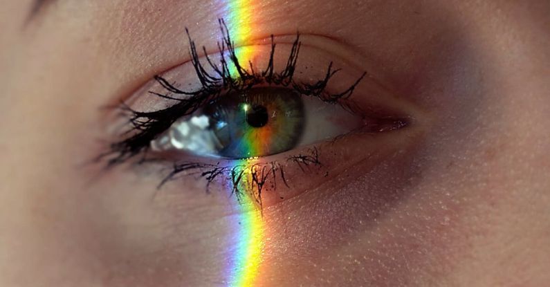Mind Mapping - Closeup of crop anonymous sad female with green eyes and rainbow light on face looking at camera