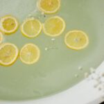 Personal Style - From above of white tub with clear water near burning candles and blooming flowers in modern bathroom during skincare treatment