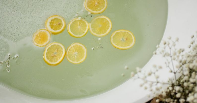 Personal Style - From above of white tub with clear water near burning candles and blooming flowers in modern bathroom during skincare treatment